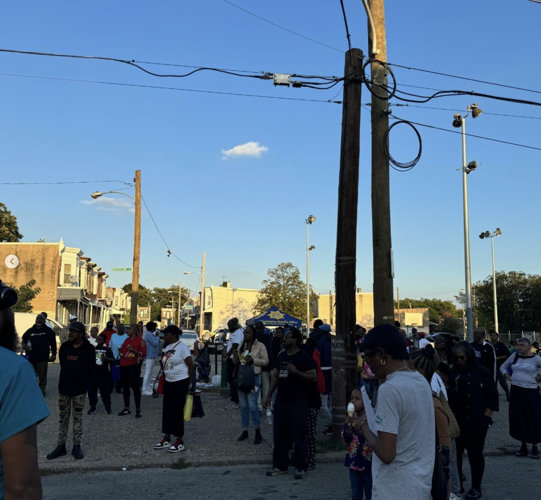 A crowd gathers on the street at sunset